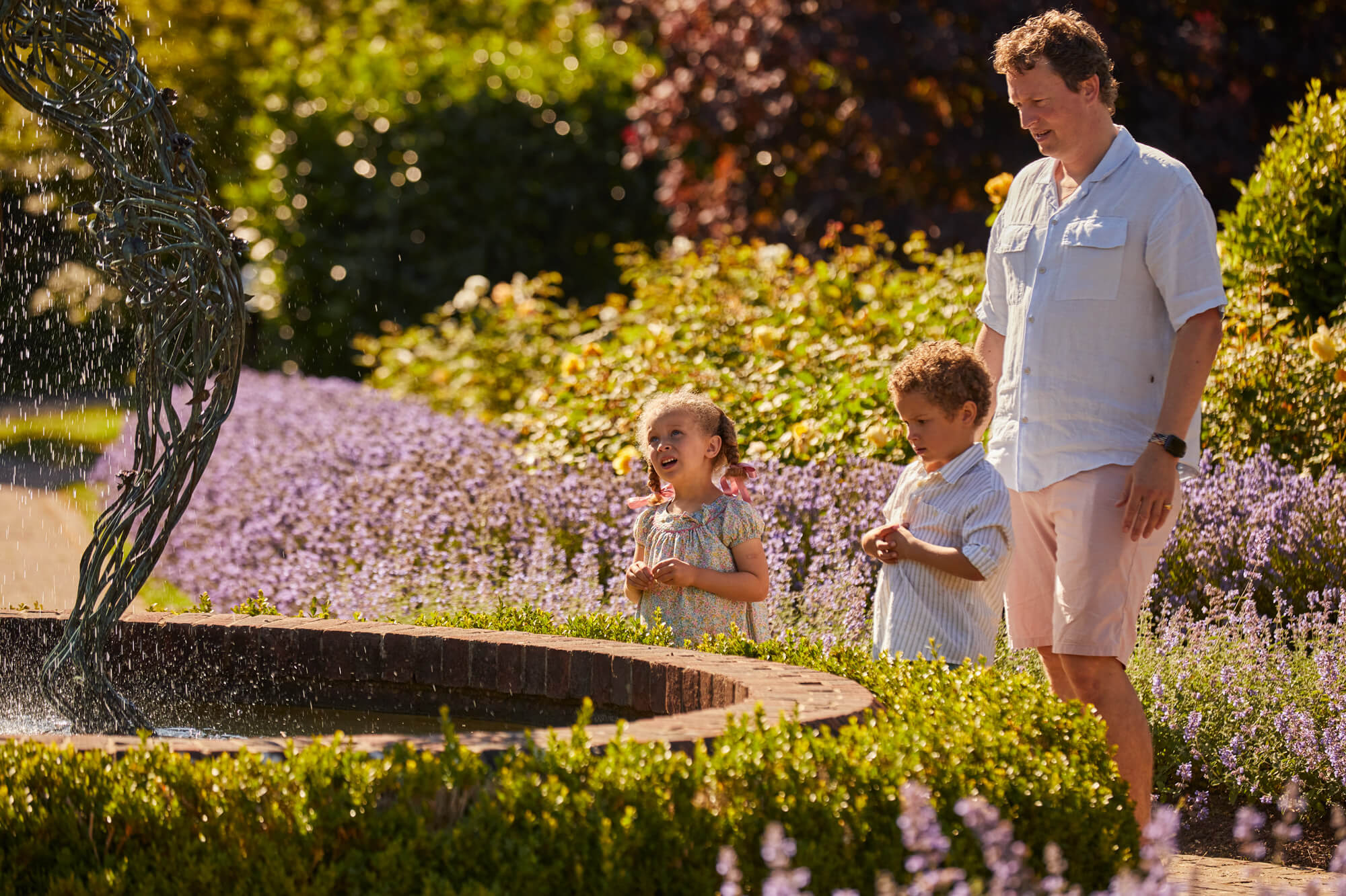 A family next to the water feature in the Rose Garden at Borde Hill during summer.